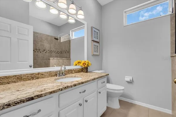 a bathroom with a granite countertop toilet sink and mirror