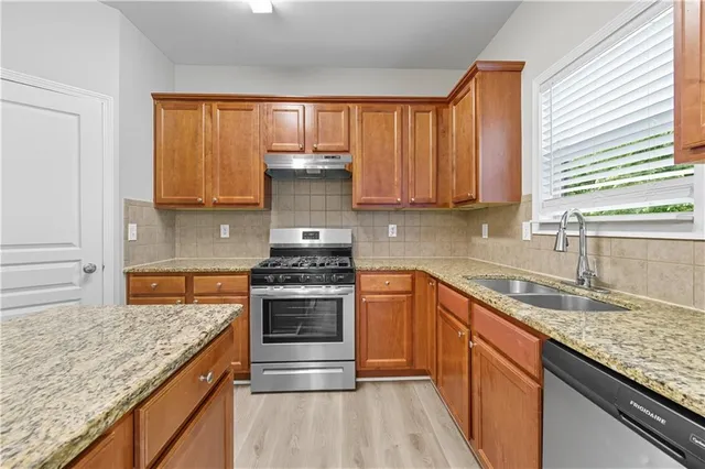 a kitchen with stainless steel appliances granite countertop a stove a sink and a granite counter tops