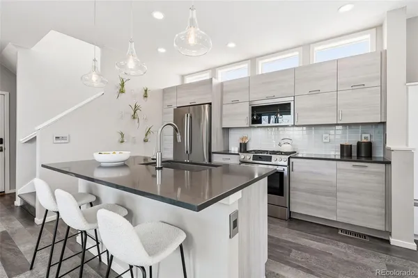 a kitchen with stainless steel appliances granite countertop a sink a stove a refrigerator cabinets and a dining table with wooden floor