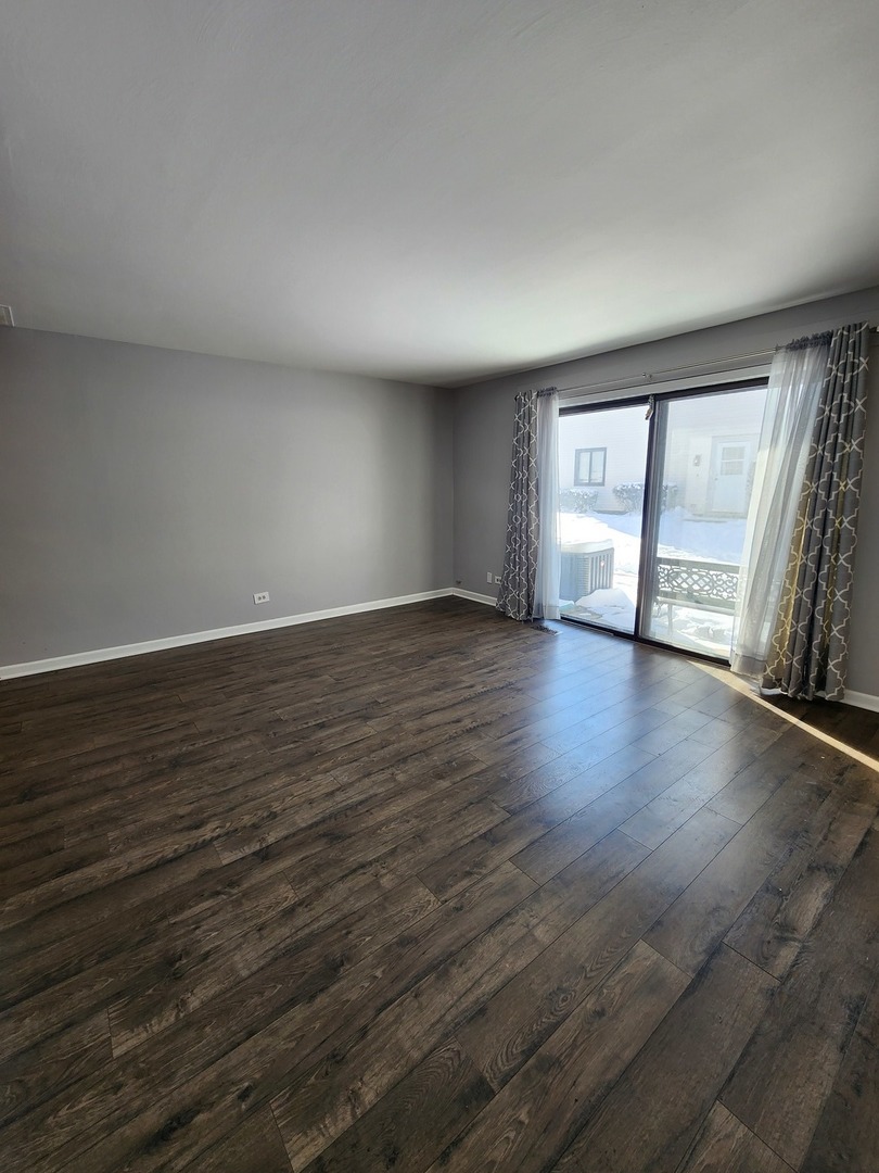 123 Brewster Court, Unit B Bloomingdale, IL 60108 - Photo 14 of 23 a view of an empty room with wooden floor and a window
