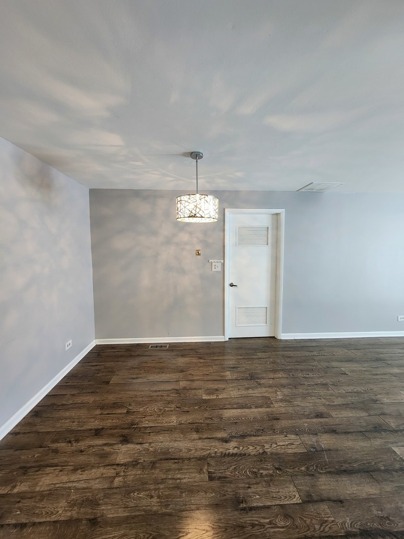 123 Brewster Court, Unit B Bloomingdale, IL 60108 - Photo 9 of 23 a view of an empty room with wooden floor and a ceiling fan