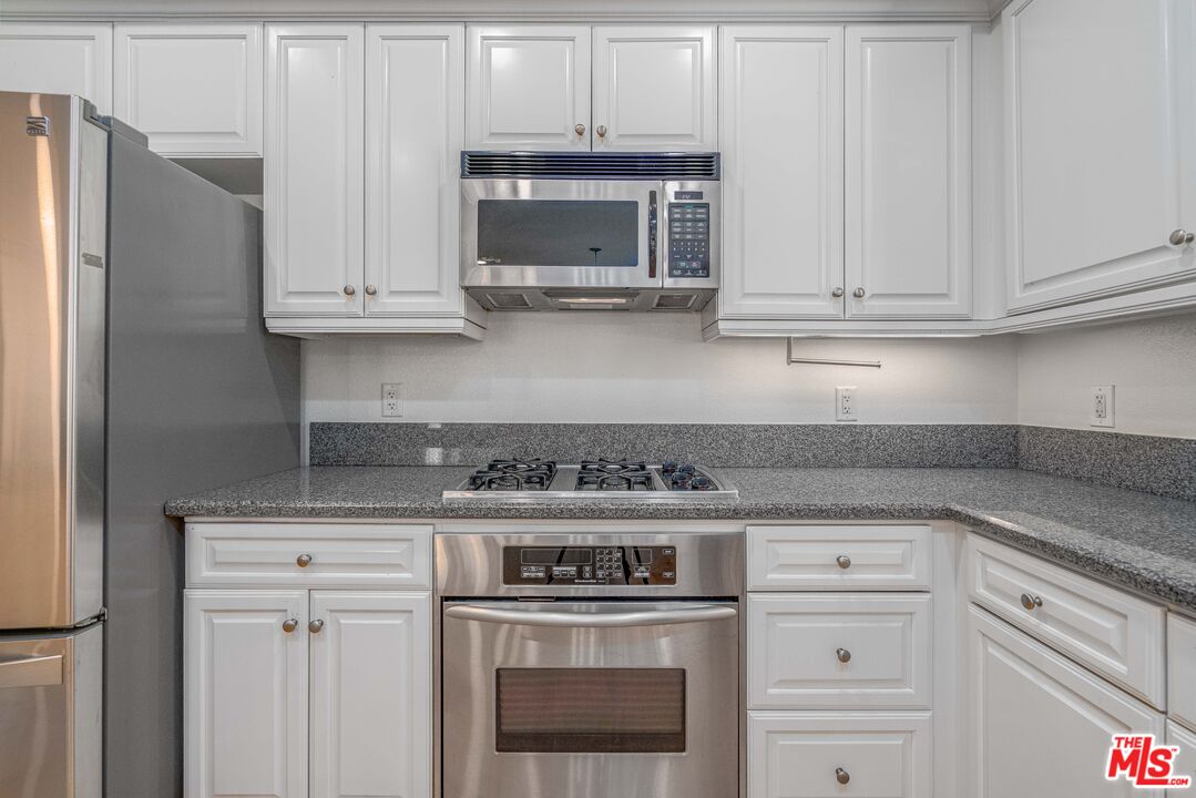 13080 Pacific Promenade, Unit 109 Playa Vista, CA 90094 - Photo 10 of 60 a kitchen with granite countertop white cabinets and stainless steel appliances