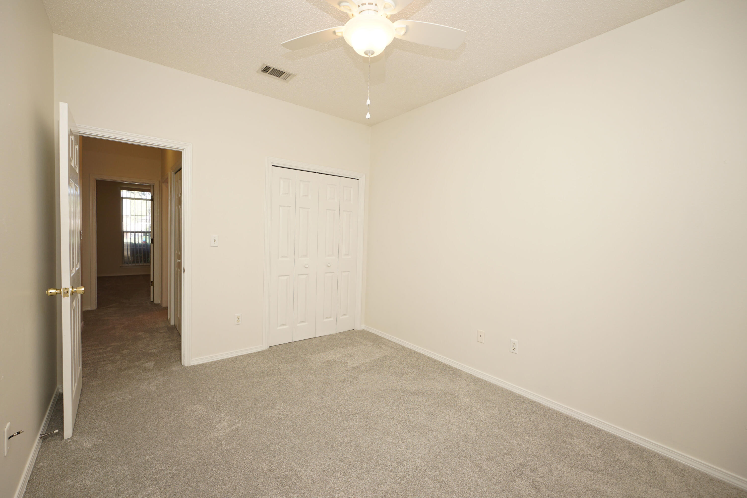 4505 Parkwood Square Niceville, FL 32578 - Photo 19 of 30 an empty room with a chandelier fan and a window