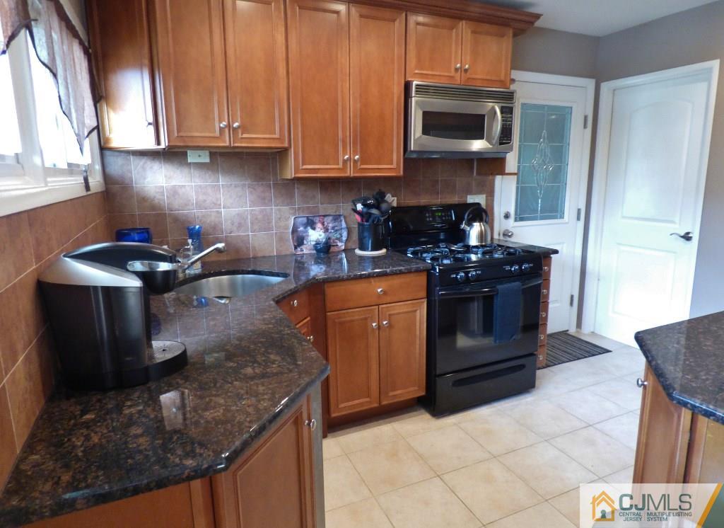 20 Clemson Road Old Bridge, NJ 08859 - Photo 7 of 25 a kitchen with stainless steel appliances granite countertop a stove a sink and a microwave