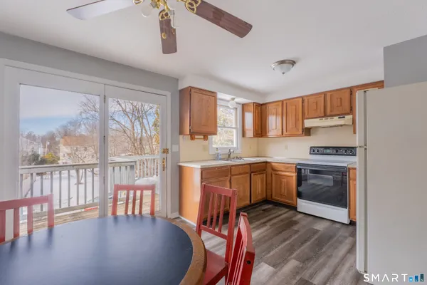 a kitchen with stainless steel appliances granite countertop a stove a sink dishwasher a microwave oven and a dining table with wooden floor