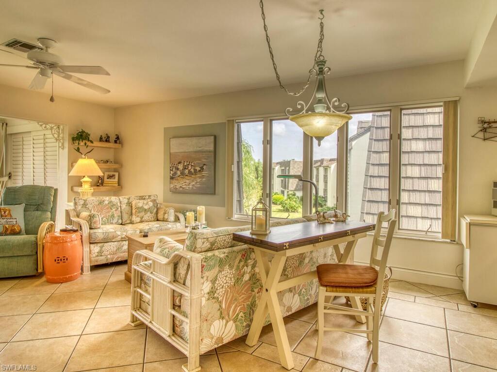 1633 Spoonbill Lane, Unit 1633C Naples, FL 34105 - Photo 16 of 35 a living room with fireplace furniture and a chandelier