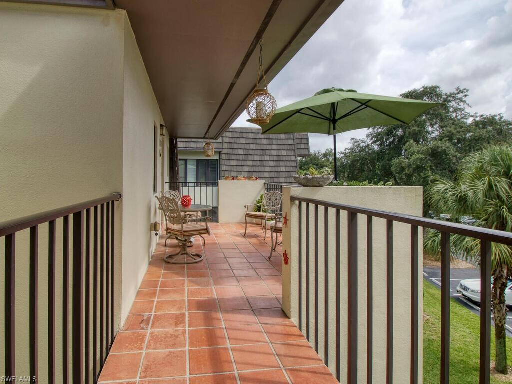 1633 Spoonbill Lane, Unit 1633C Naples, FL 34105 - Photo 2 of 35 a view of a patio with a table and chairs under an umbrella
