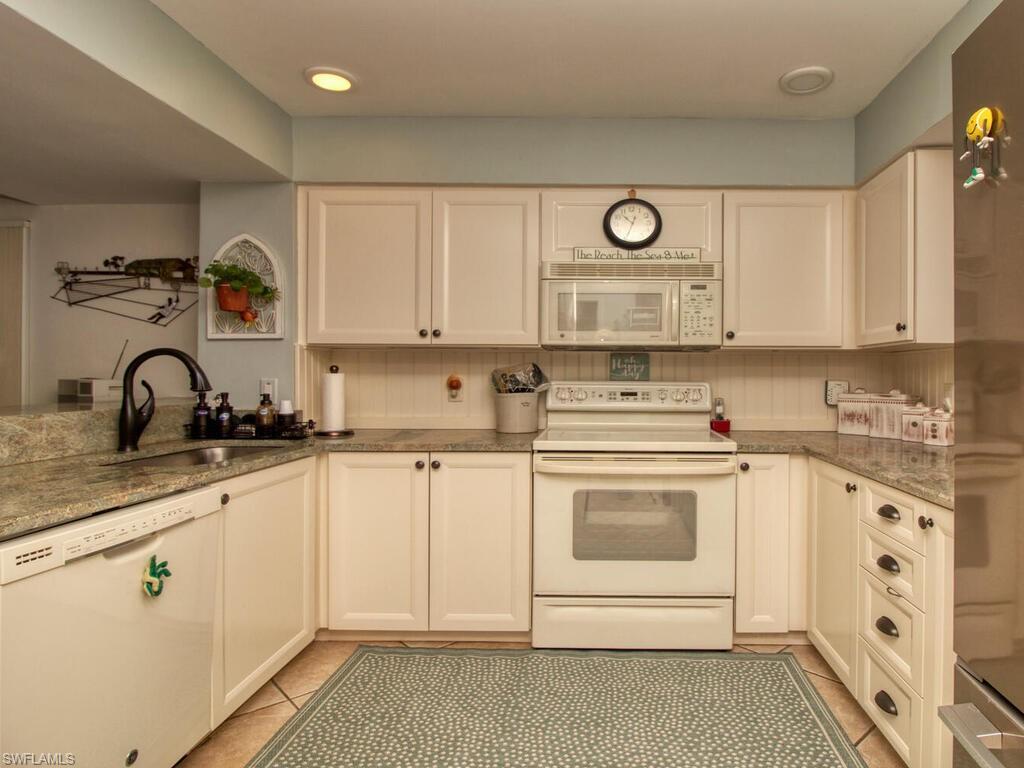 1633 Spoonbill Lane, Unit 1633C Naples, FL 34105 - Photo 7 of 35 a kitchen with granite countertop white cabinets and white appliances
