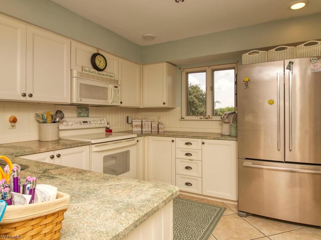 1633 Spoonbill Lane, Unit 1633C Naples, FL 34105 - Photo 8 of 35 a kitchen with stainless steel appliances granite countertop a refrigerator sink and white cabinets