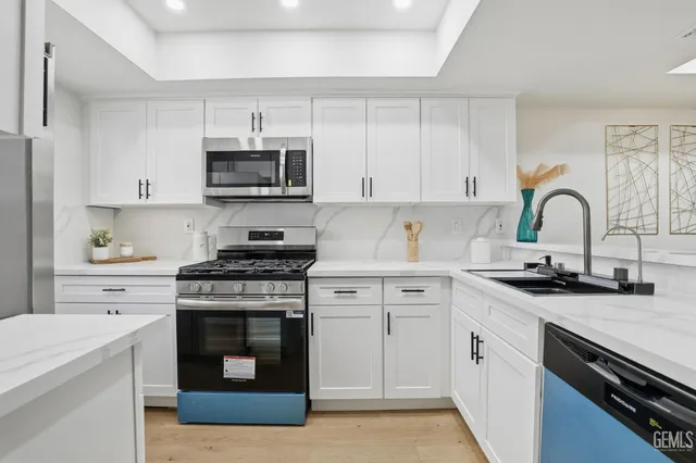 a kitchen with stainless steel appliances granite countertop a stove a sink and a refrigerator
