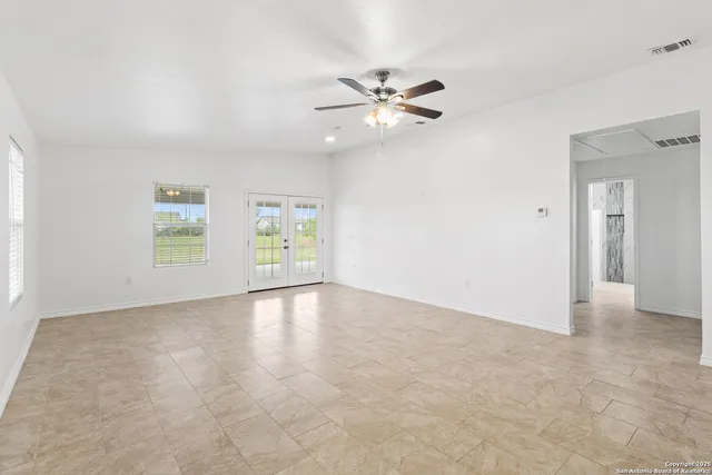 a view of an empty room with chandelier fan and fire place