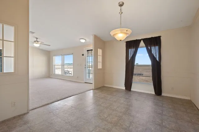 a view of a room with large windows and ceiling fan