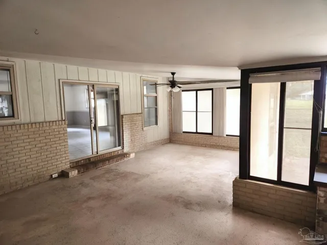 an empty room with windows and fan