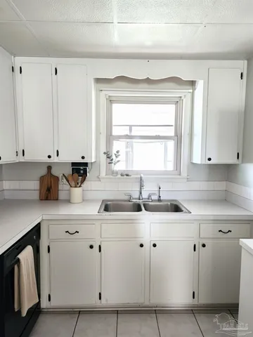 a kitchen with white cabinets sink and window