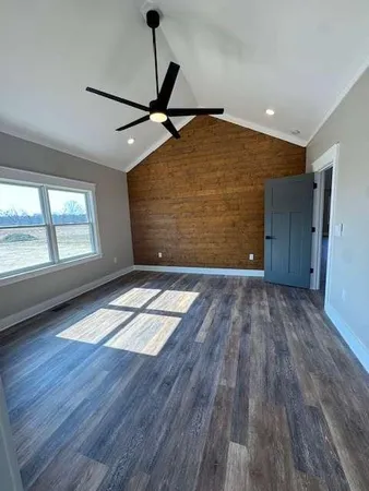 a view of empty room with wooden floor and fan