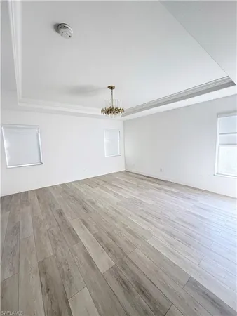 a view of an empty room with wooden floor and window