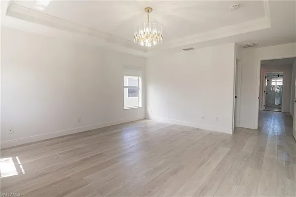 an empty room with wooden floor ceiling fan and windows