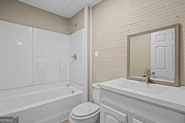 a bathroom with a bathtub shower sink vanity and toilet