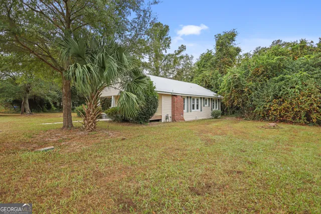 a view of a house with backyard and trees