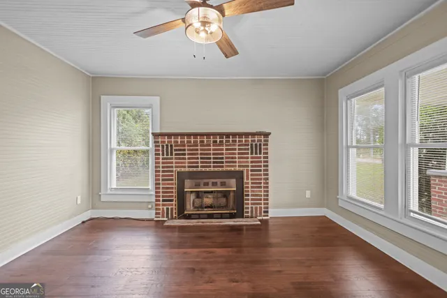 an empty room with wooden floor fireplace and windows