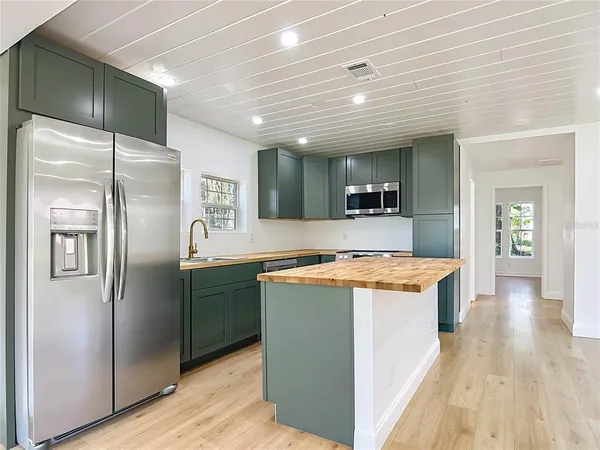 a kitchen with stainless steel appliances granite countertop a refrigerator a stove and a wooden floors