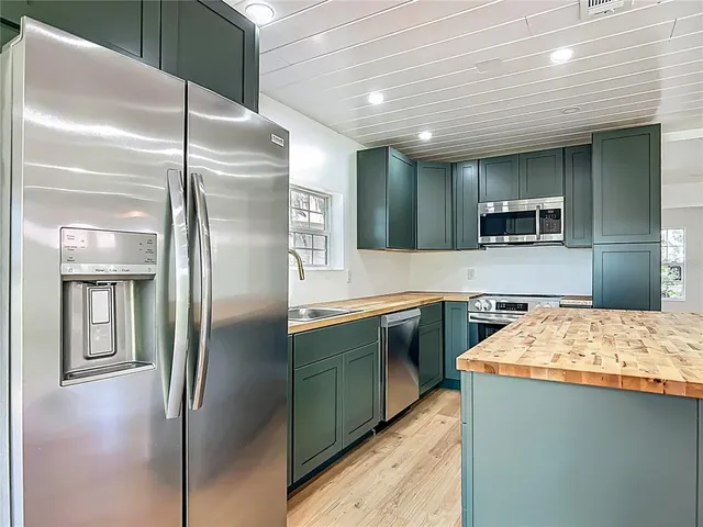 a kitchen with stainless steel appliances granite countertop a refrigerator a sink and a stove