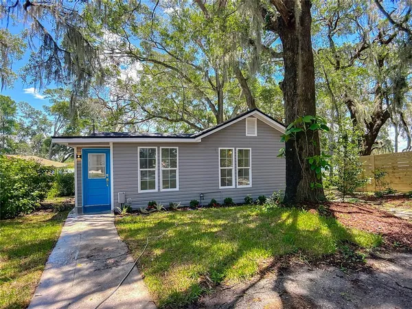 a view of a house with a yard and large tree