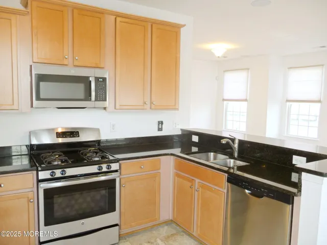 a kitchen with granite countertop cabinets stainless steel appliances and a window