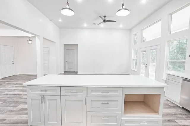 a kitchen with granite countertop a stove a sink and white cabinets with wooden floor