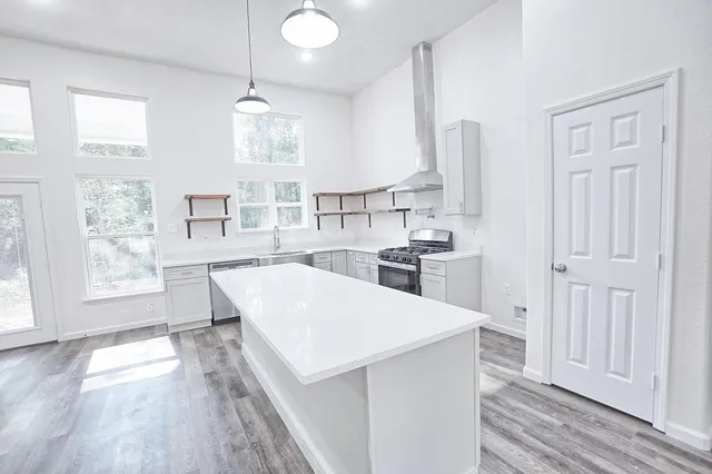 a large white kitchen with lots of counter space wooden floor and appliances