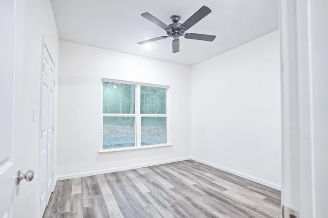 an empty room with a window and a ceiling fan