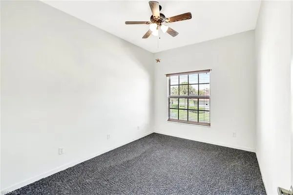 an empty room with a window and a fan
