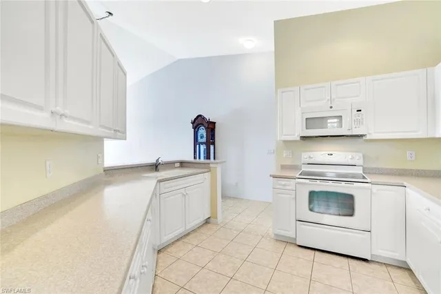 a kitchen with granite countertop white cabinets and white appliances