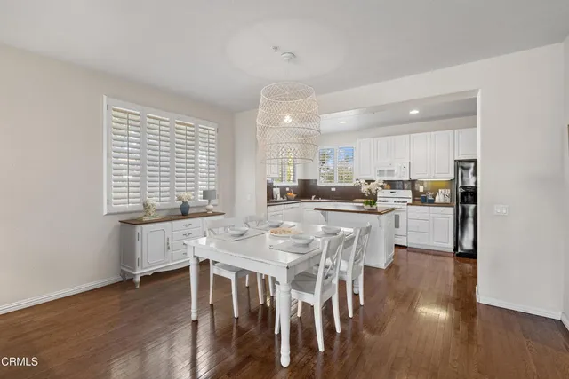a kitchen with stainless steel appliances kitchen island granite countertop a dining table chairs and white cabinets