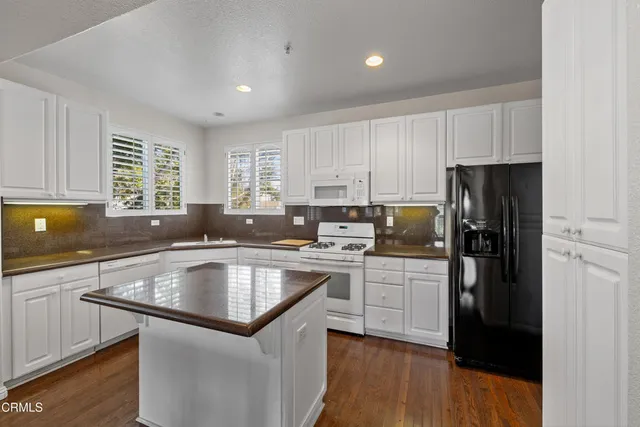 a kitchen with kitchen island granite countertop a sink stove and refrigerator
