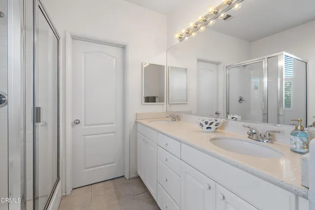 a bathroom with a double vanity sink mirror and shower
