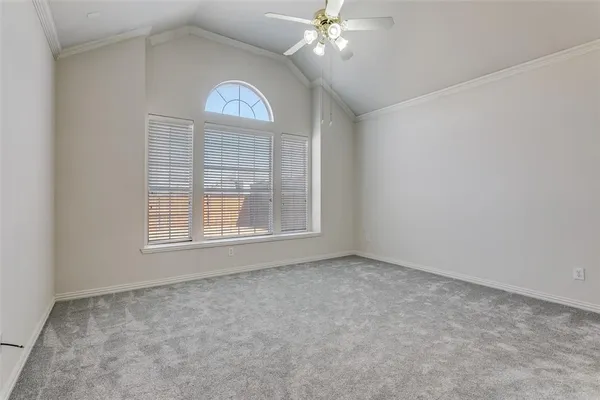 an empty room with a chandelier fan and windows
