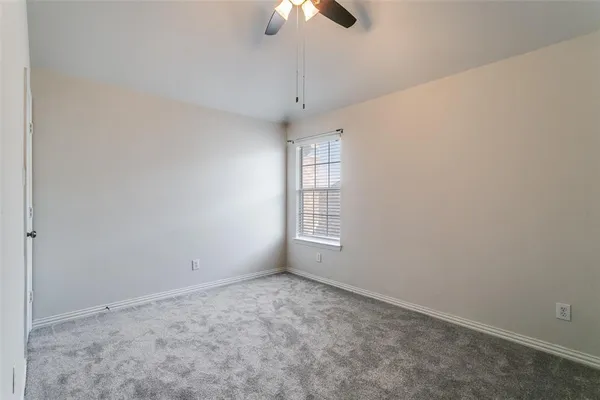 an empty room with chandelier fan and windows