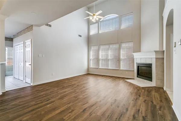 an empty room with wooden floor fireplace and windows