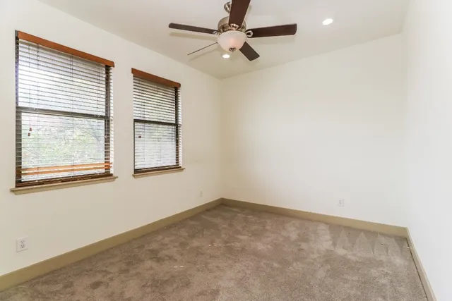 an empty room with a window and a fan
