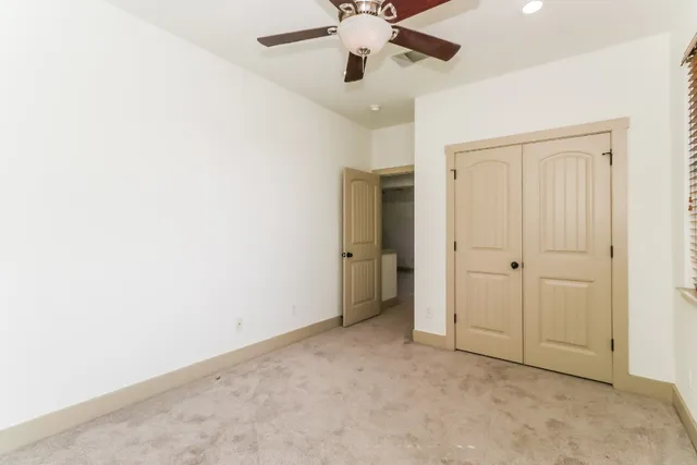 an empty room with a ceiling fan and a window