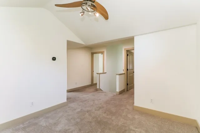 an empty room with a chandelier fan and refrigerator