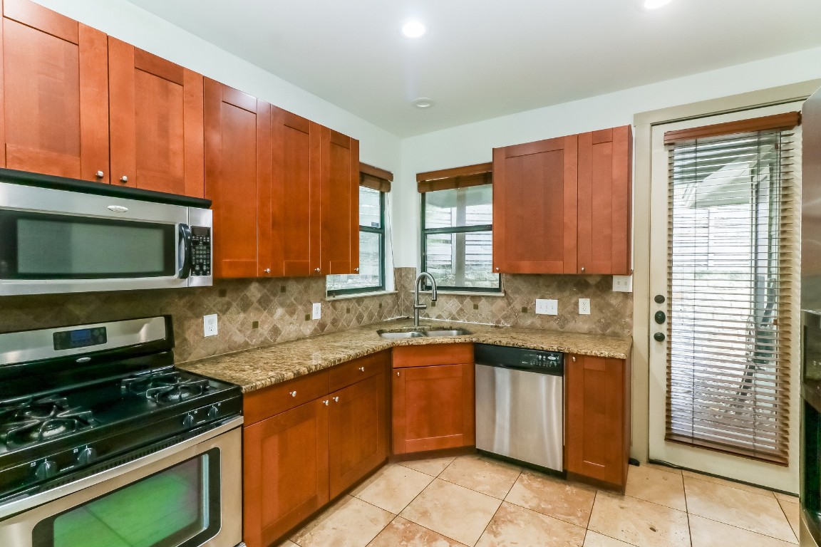 1212 Woodland Avenue, Unit A Austin, TX 78704 - Photo 6 of 20 a kitchen with stainless steel appliances a stove sink microwave and cabinets