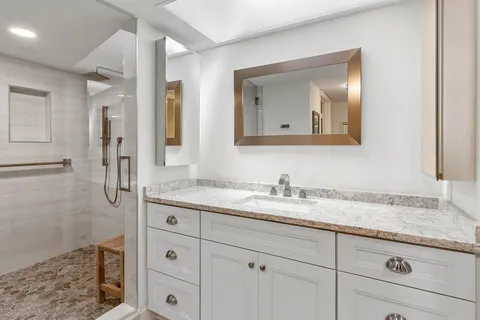a bathroom with a granite countertop sink two mirror and a