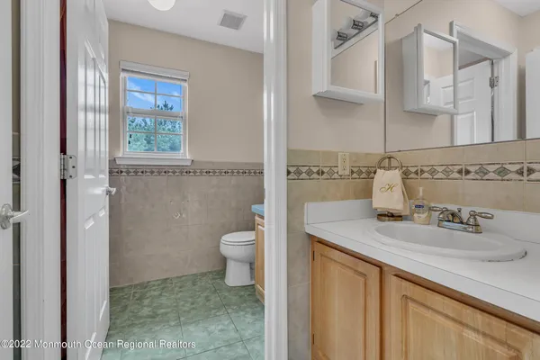 a bathroom with a granite countertop sink a toilet and a mirror