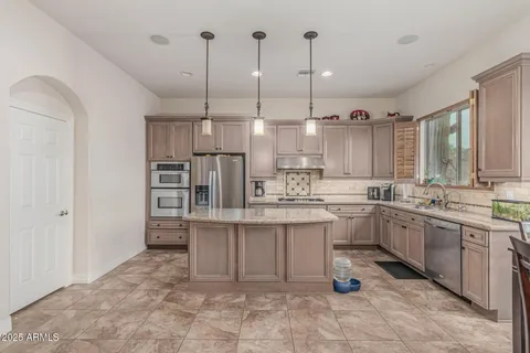 a large kitchen with kitchen island a sink stove and white cabinets