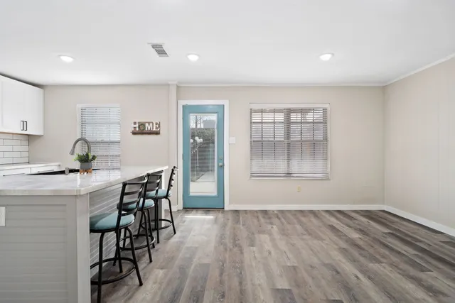 a kitchen with granite countertop a stove a sink a dining table and chairs
