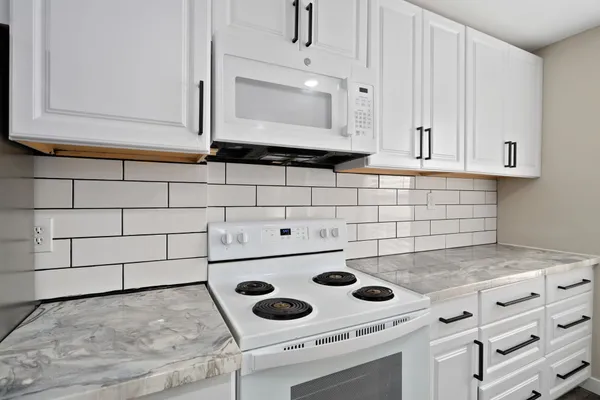 a stove top oven sitting inside of a kitchen and white cabinets