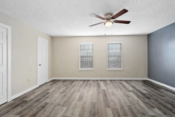 a view of empty room with wooden floor and ceiling fan
