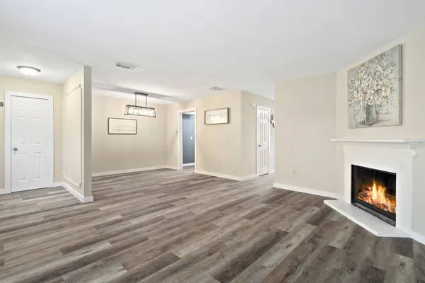 a view of an empty room with wooden floor fireplace and a window